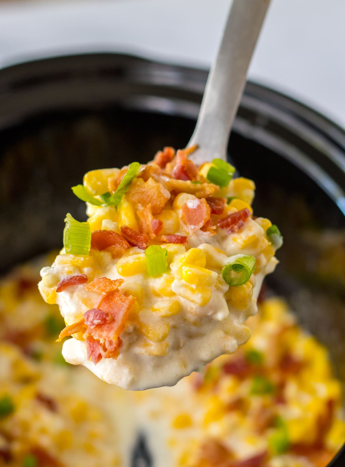 spoon of crock pot creamed corn with bacon