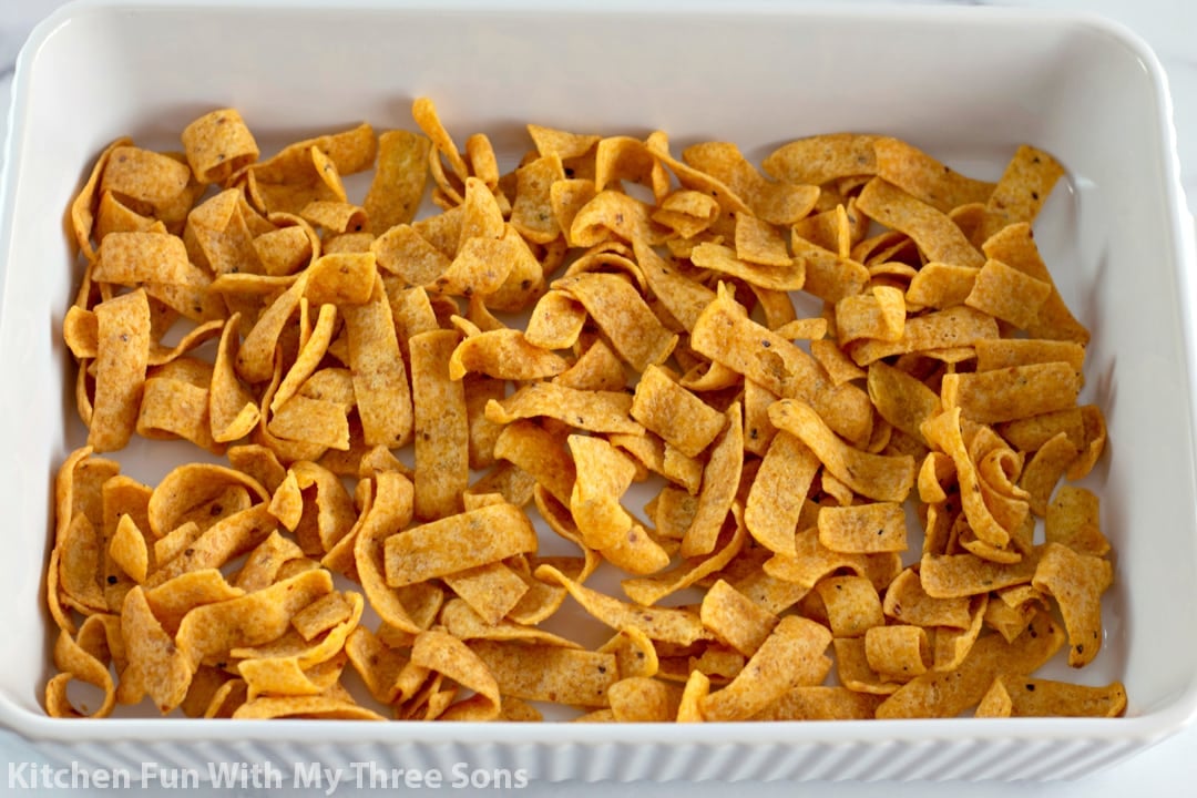 A casserole dish with a layer of Fritos in the bottom.