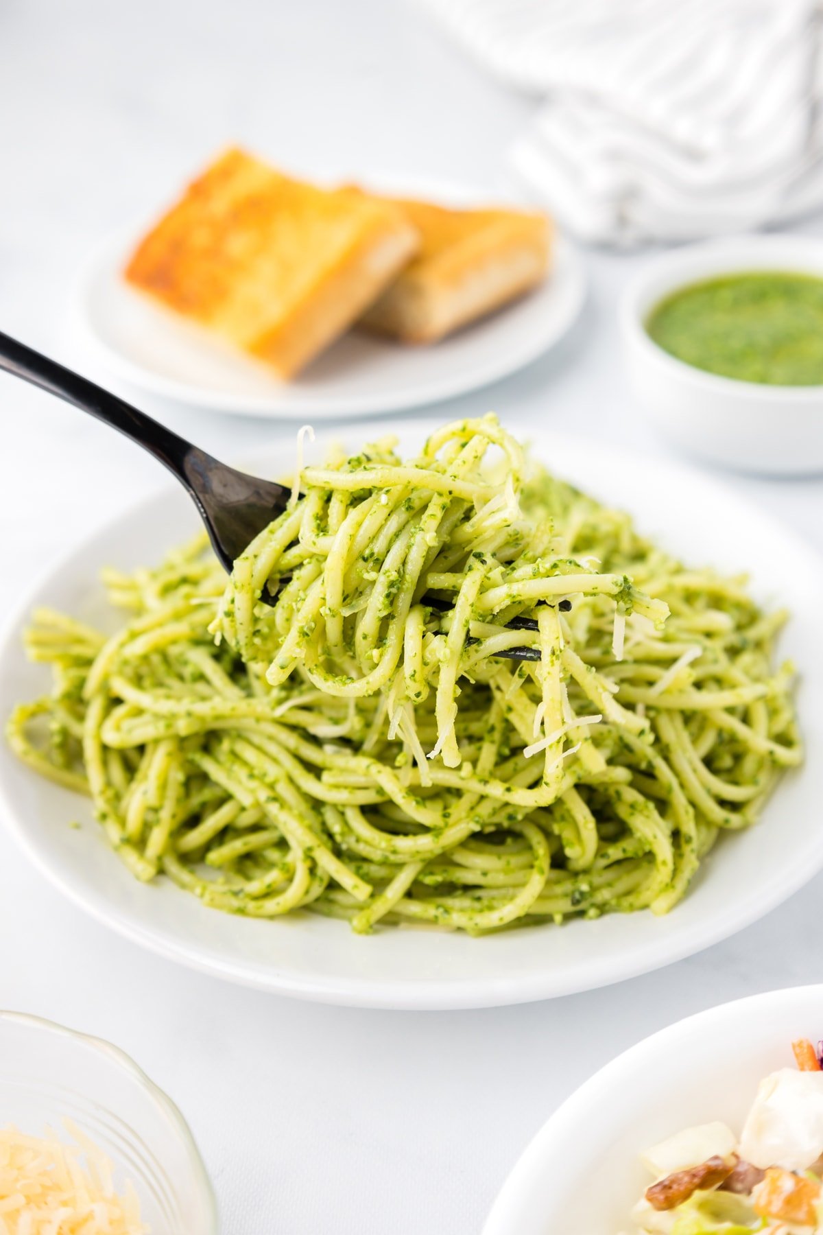 A fork in a bowl of pesto pasta